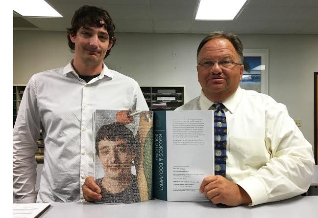 Right to left: Johnston County Register of Deeds Craig Olive and Jeff Wilson, the offices’s computer systems analyst, display a copy of Tyler Technologies annual report which features the technology advances made at the Register of Deeds Office in recent years. Contributed photo