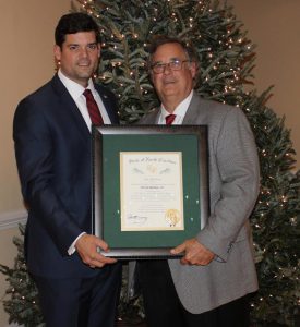 (Left to right) DeVan Barbour, IV presents his father, retiring Johnston County Commissioner DeVan Barbour, III the Order of the Long Leaf Pine during a private retirement reception at the County Club of Johnston County Thursday night.